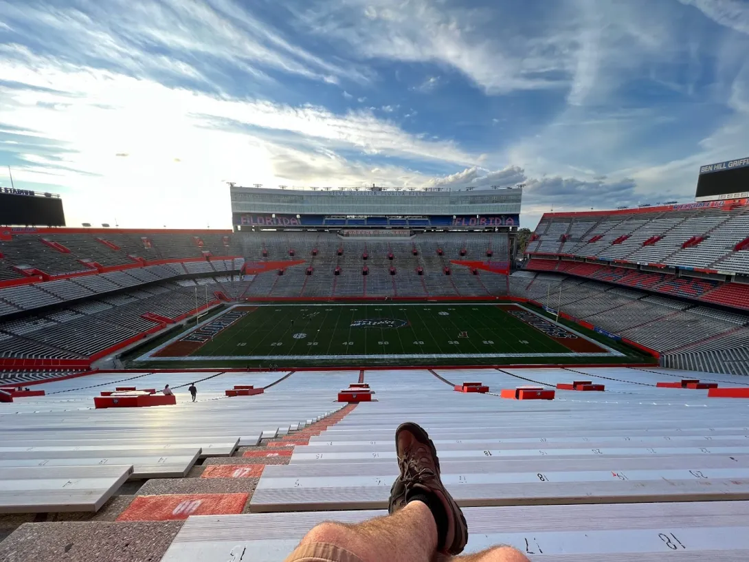 View of a very large football stadium from the top, with the photographer's feet crossed.