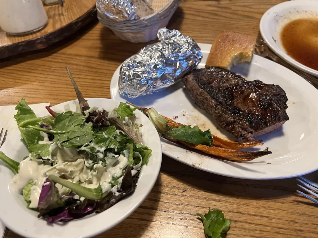 Salad bowl and a plate with a steak and potato