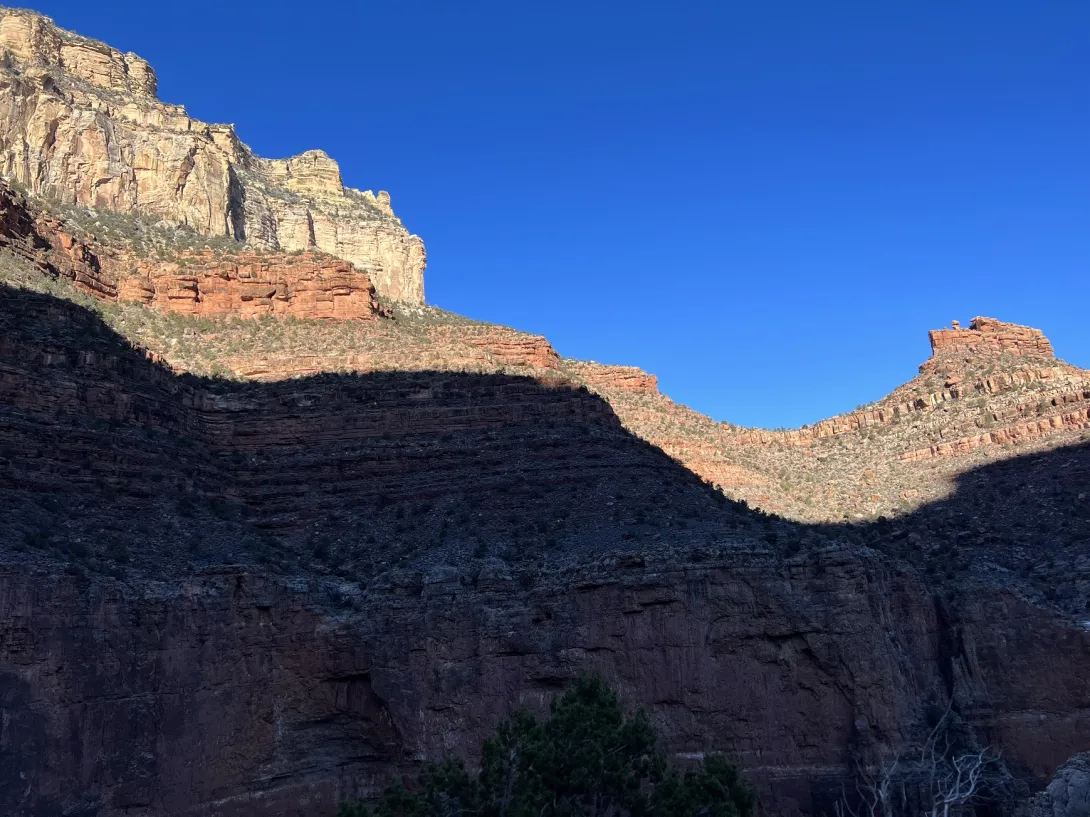Canyon wall with blue sky above and a dark shadow below
