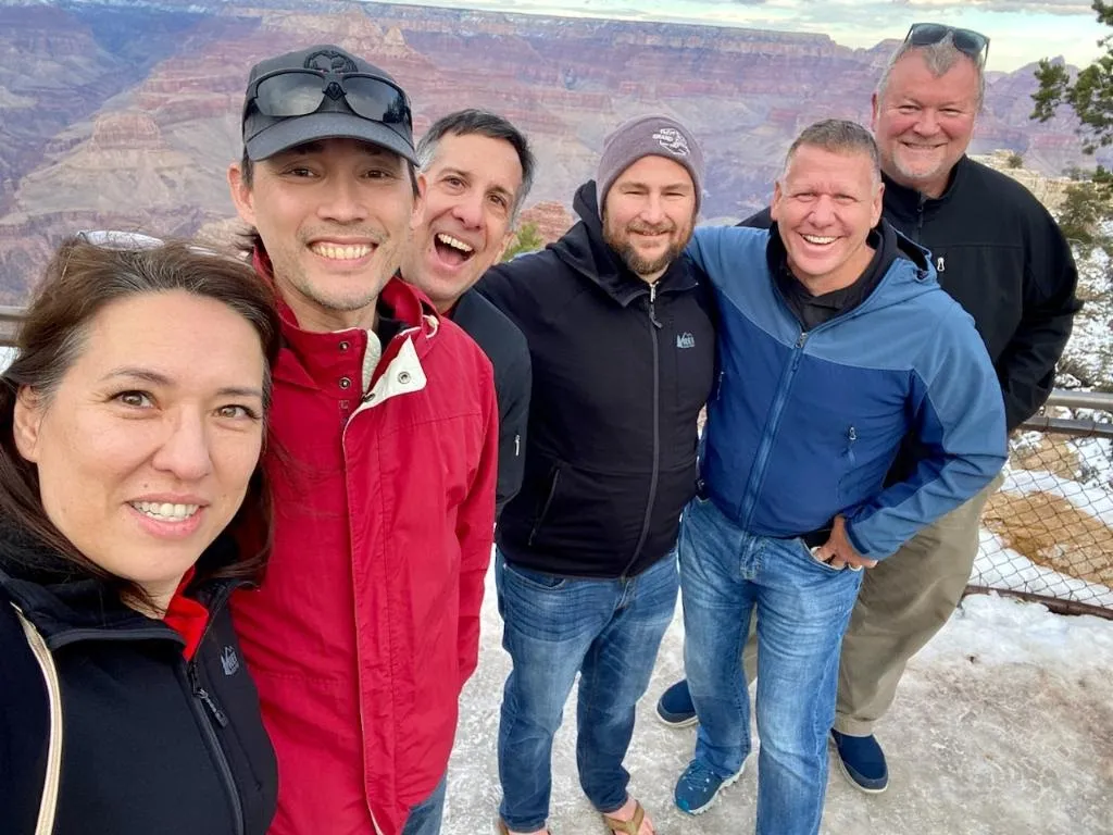 Group of people smiling for a selfie in front of the Grand Canyon