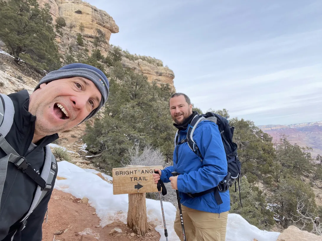 Selfie of Mike and me. Mike is making a stupid gap-jawed face. We're buy a sign that says "bright angel trail". 