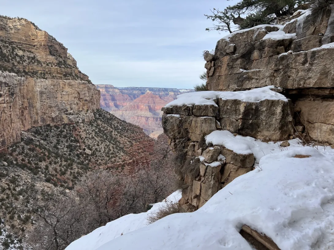 View of the canyon past rock formations with snow in the foreground