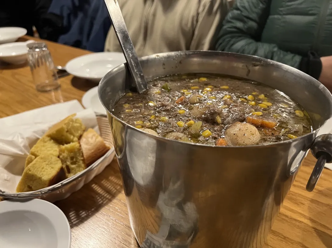 Close up to a pot of hearty stew. You can see beef and corn and potatos in it