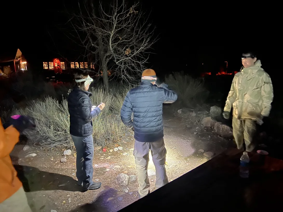 group of people gearing up in the dark with headlamps