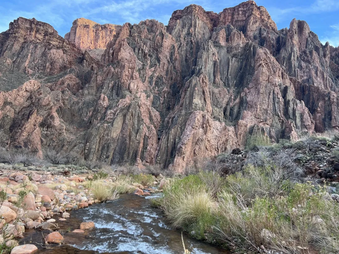 Beautiful stream with pretty vegetation in front of large rock formation