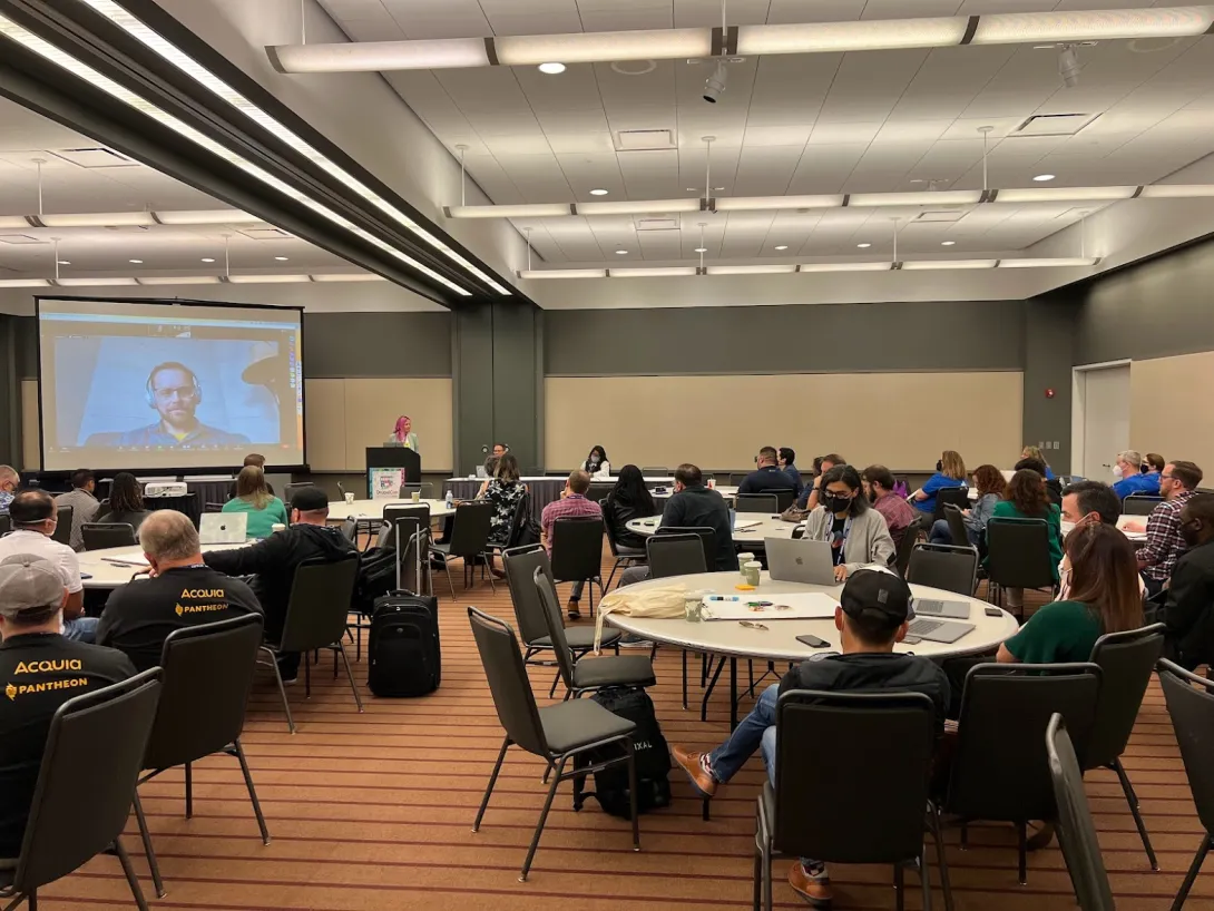 Large room with people watching the session while sitting at tables