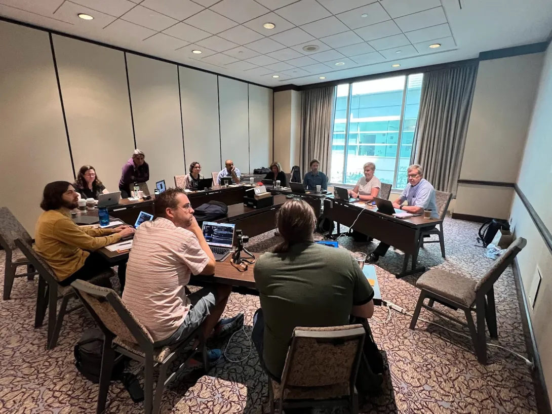 The Drupal Association Board around a meeting table in a small hotel conference room