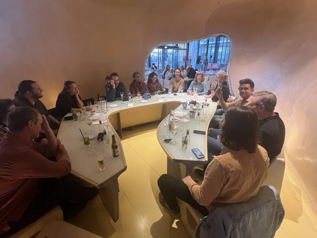 Board members sitting around a weirdly shaped table eating and laughing