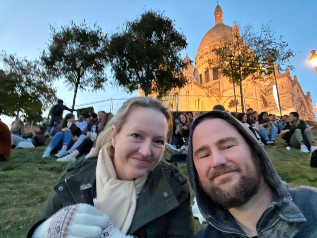 Robin and I selfie on a hill with lots of people with a beautiful lit up church in the distance