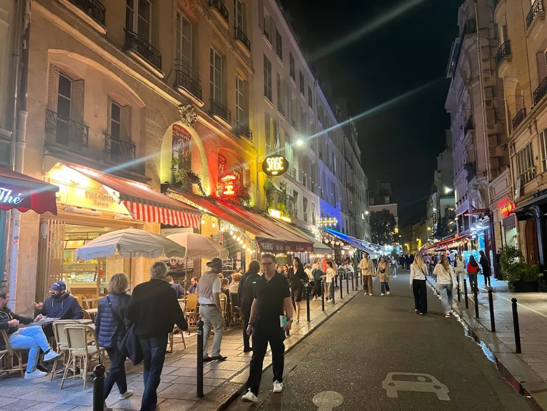 Paris street at night with people walking, street dining